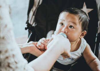 person feeding baby from feeding bottle